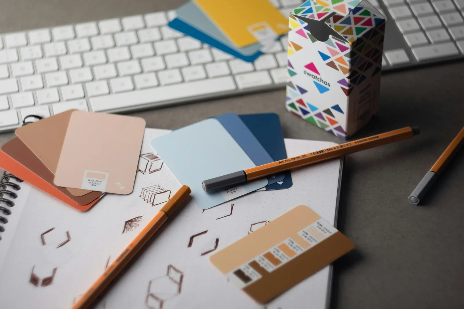 Mesa de diseño con muestras de color, lápices y herramientas de trabajo
